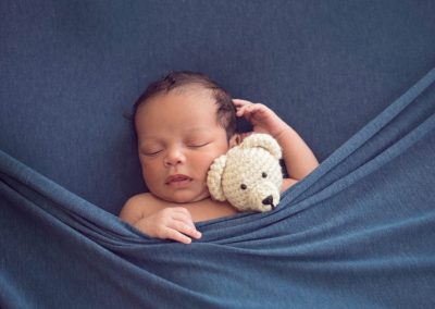 Newborn boy tucked in with blue blanket holding stuffed bear | san diego newborn photography | Book your session today: www.babiesandbeauties.com