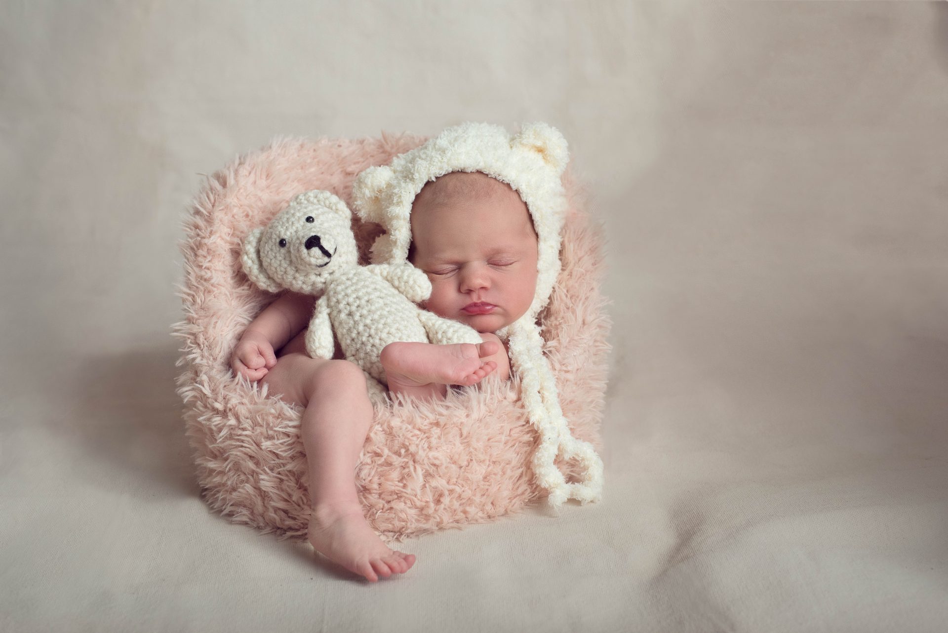 Newborn baby girl in tiny pink fur chair with stuffed bear | newborn photographer san diego | www.babiesandbeauties.com
