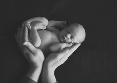 Newborn baby in dad's hands in black and white | newborn photography san diego | www.babiesandbeauties.com for more info