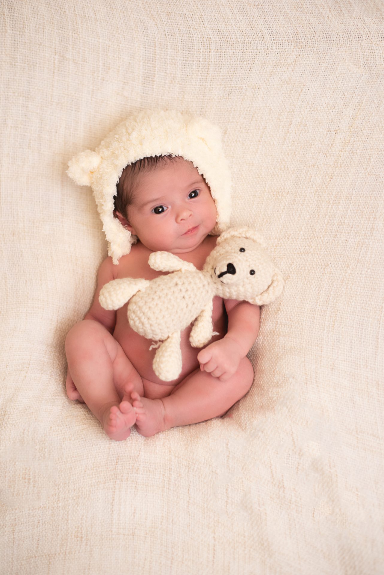 Newborn girl in cream bear bonnet with small stuffed bear | san diego baby photography | Visit www.babiesandbeauties.com