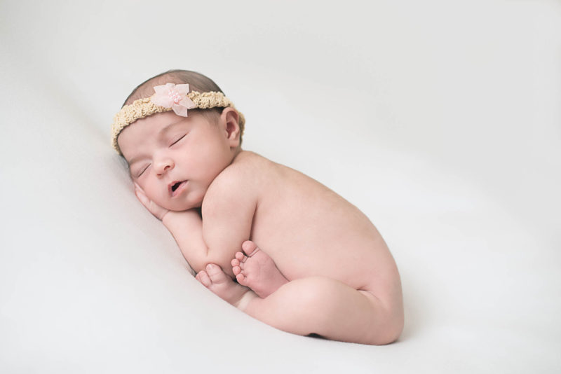 newborn baby girl with pink flower headband | san diego newborn photography | Learn more at www.babiesandbeauties.com