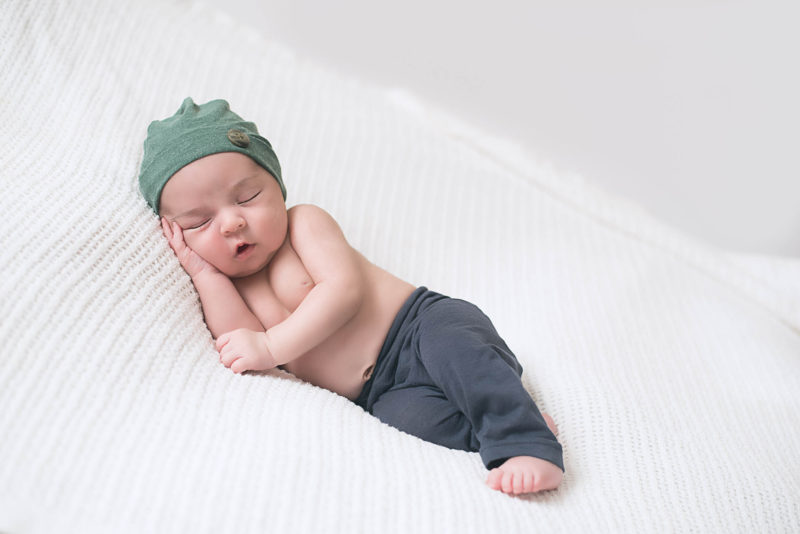 newborn baby in green cap and blue pants | newborn baby photos san diego | www.babiesandbeauties.com