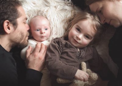 Family of 4 with two year old and newborn snuggled on flokati rug | san diego newborn photography | Visit www.babiesandbeauties.com to learn more!