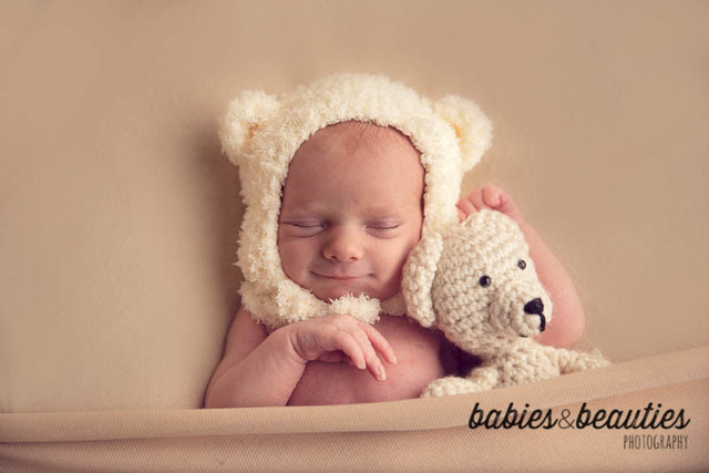 newborn baby wearing bear bonnet hugging stuffed bear | newborn photography san diego | Visit www.babiesandbeauties.com