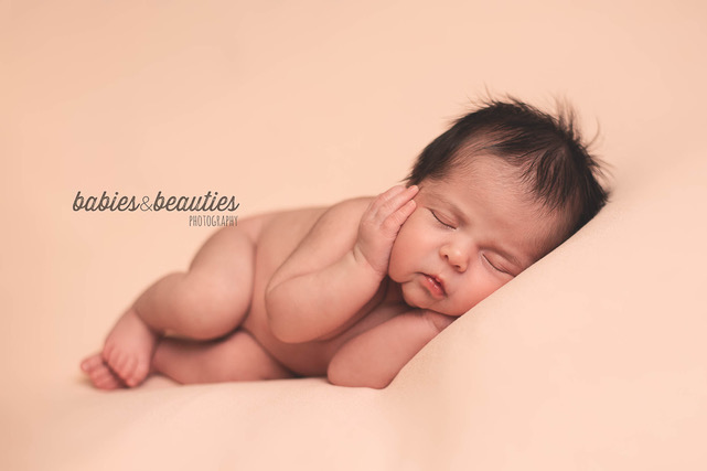 newborn baby girl with hands on cheeks on pick background | newborn photography San Diego | Visit www.babiesandbeauties.com