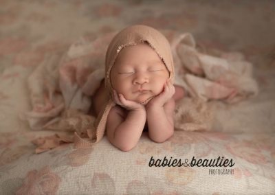Newborn photo of baby with head in hands on antique floral background | Newborn photography in san diego | Visit www.babiesandbeauties.com
