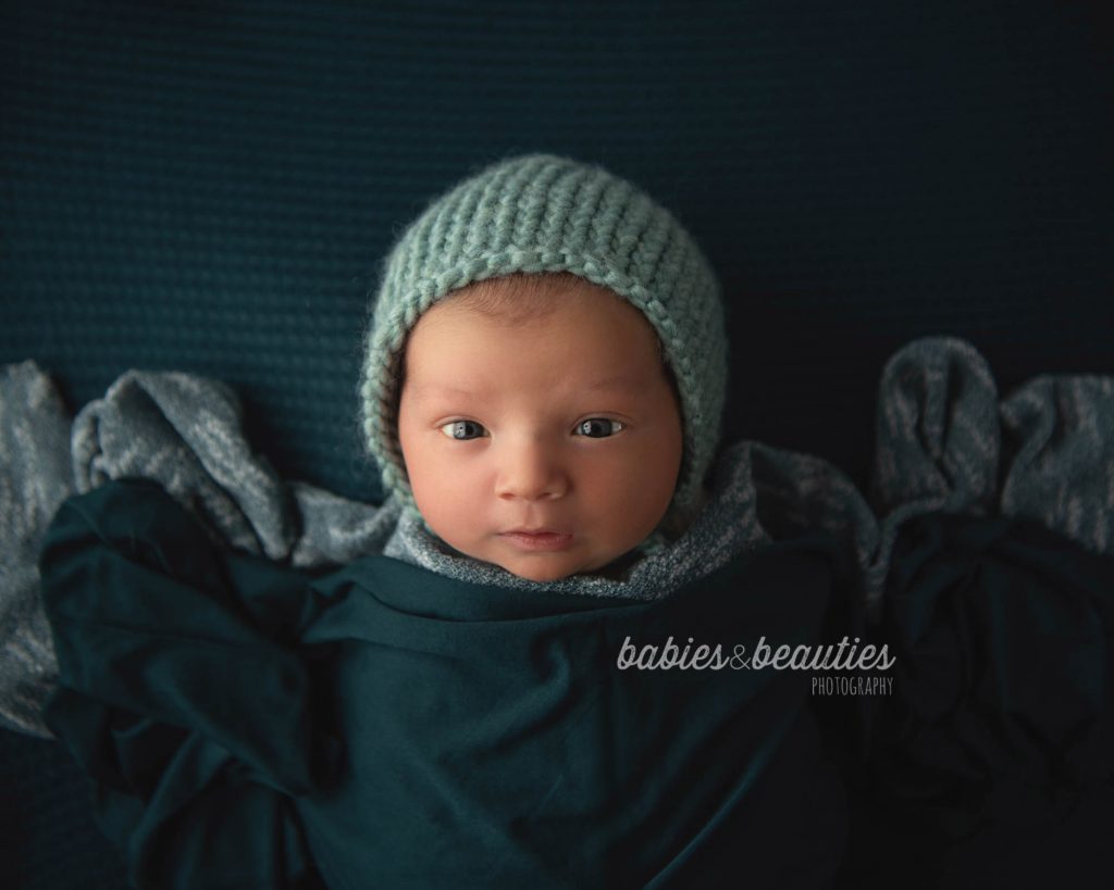 Newborn photography of little boy in teal outfit with bonnet. Let's chat about your newborn photos! 