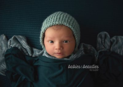 Newborn photography of little boy in teal outfit with bonnet | Newborn photography san diego | Let's book your session today!
