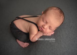 Newborn photography of little boy in grey suspenders. Let's book your newborn session today! www.babiesandbeauties.com