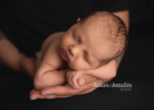 Newborn photo of baby in dad's hands. Contact us today to book your newborn session!