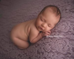 Newborn photography of a little girl on violet flower background. Book your newborn session with Babies and Beauties today! www.babiesandbeauties.com