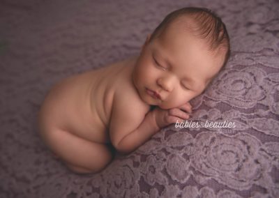 Newborn photography of a little girl on violet flower background. Book your newborn session with Babies and Beauties today! www.babiesandbeauties.com