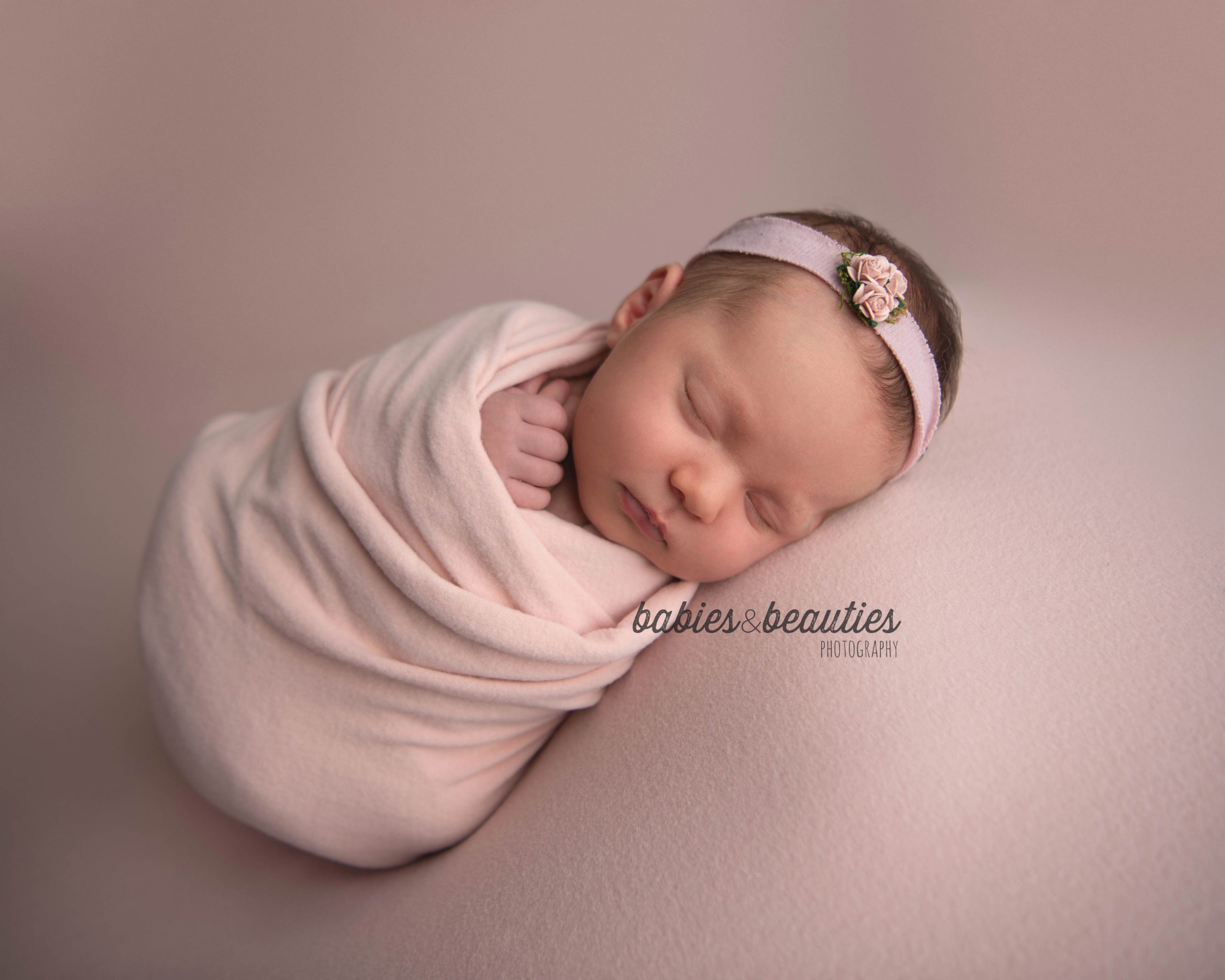 Baby girl in pink wrap with pink floral headband | san diego newborn photography | Visit www.babiesandbeauties.com to learn more!