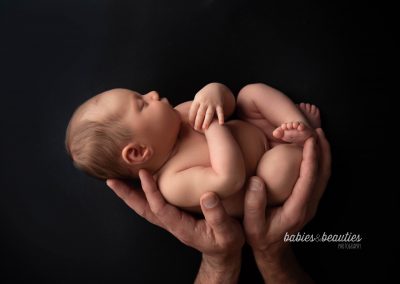 Newborn baby girl in dad's hands | newborn photography in san diego | Visit www.babiesandbeauties.com to learn more!