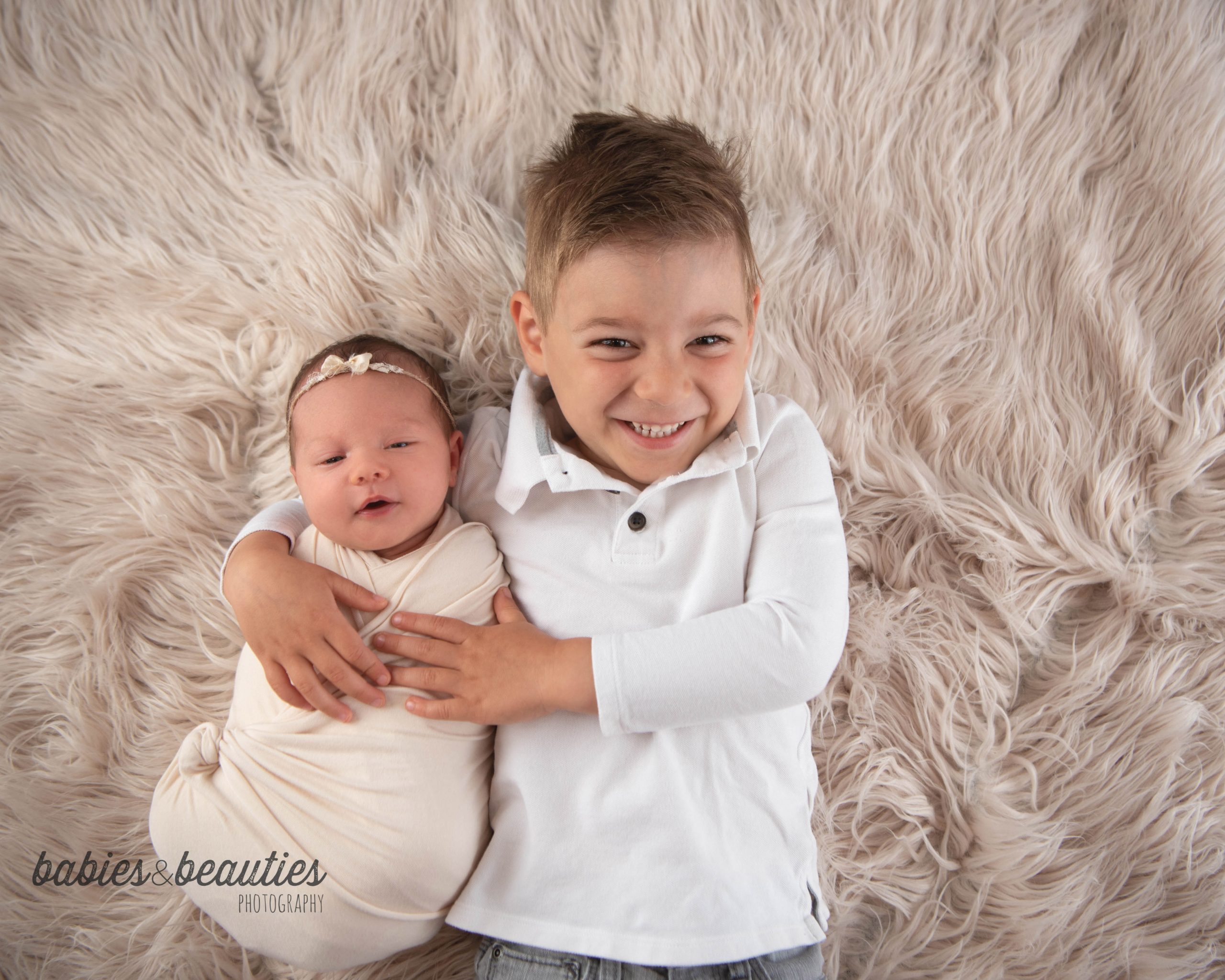 Newborn with big brother on cream fur | newborn photography in san diego | Visit www.babiesandbeauties.com to learn more!
